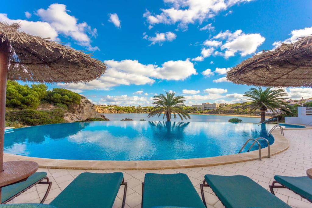 a swimming pool with chairs and umbrellas at White sands 613 in Arenal d'en Castell