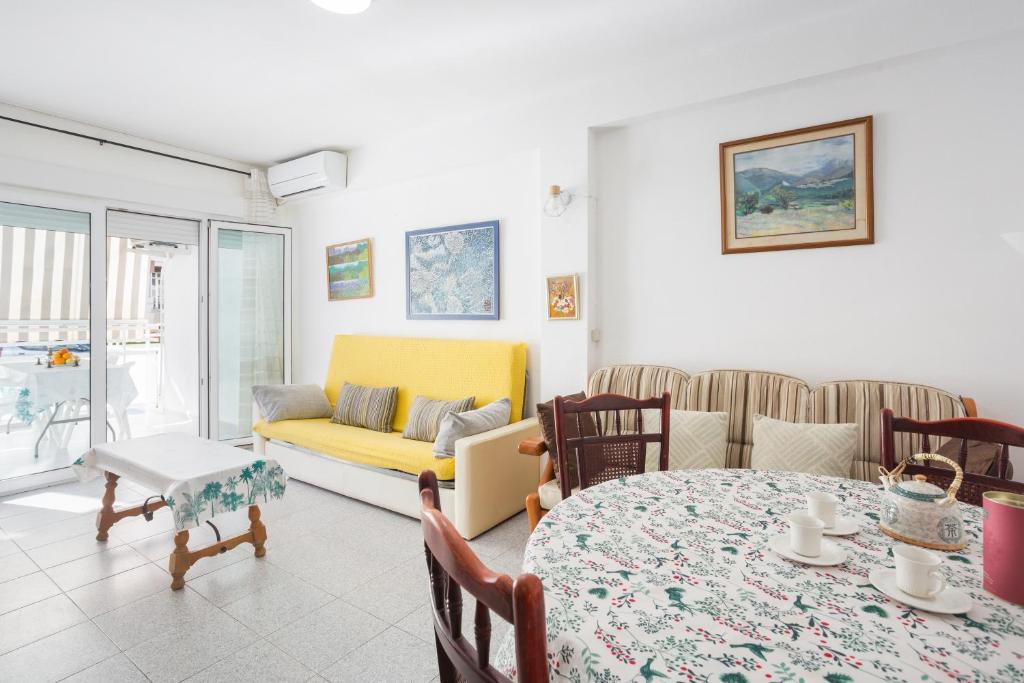 ein Wohnzimmer mit einem Tisch und einem gelben Sofa in der Unterkunft Ca Llaurí in Daimús