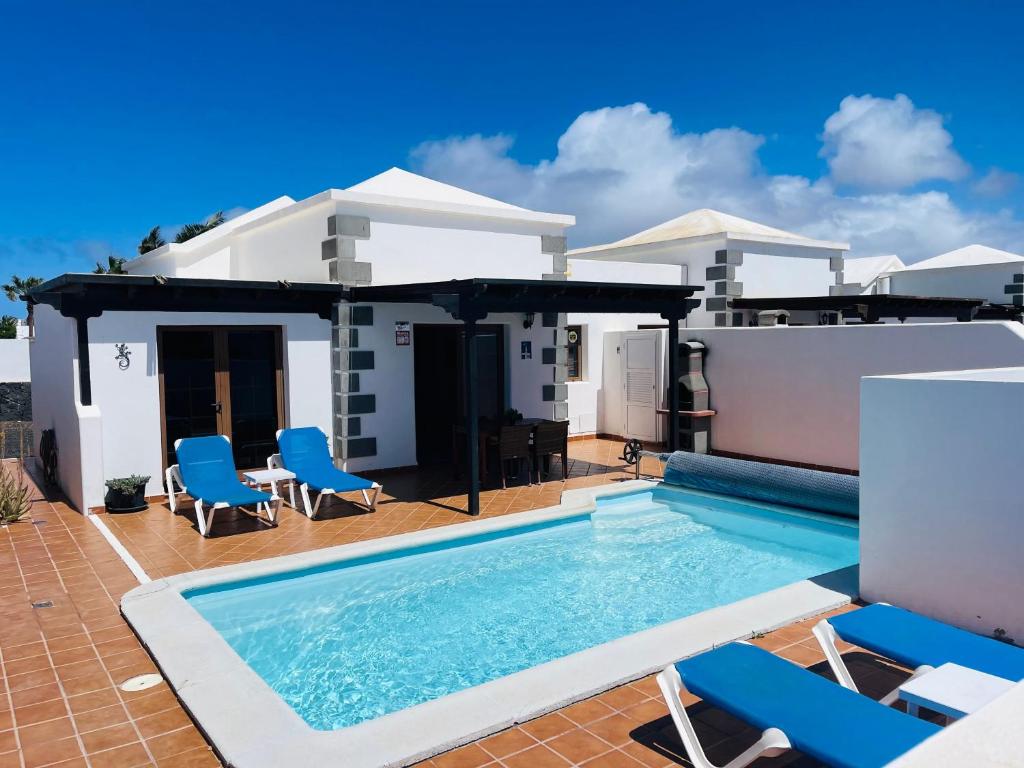 a villa with a swimming pool and blue chairs at Villa Gauda in Lanzarote