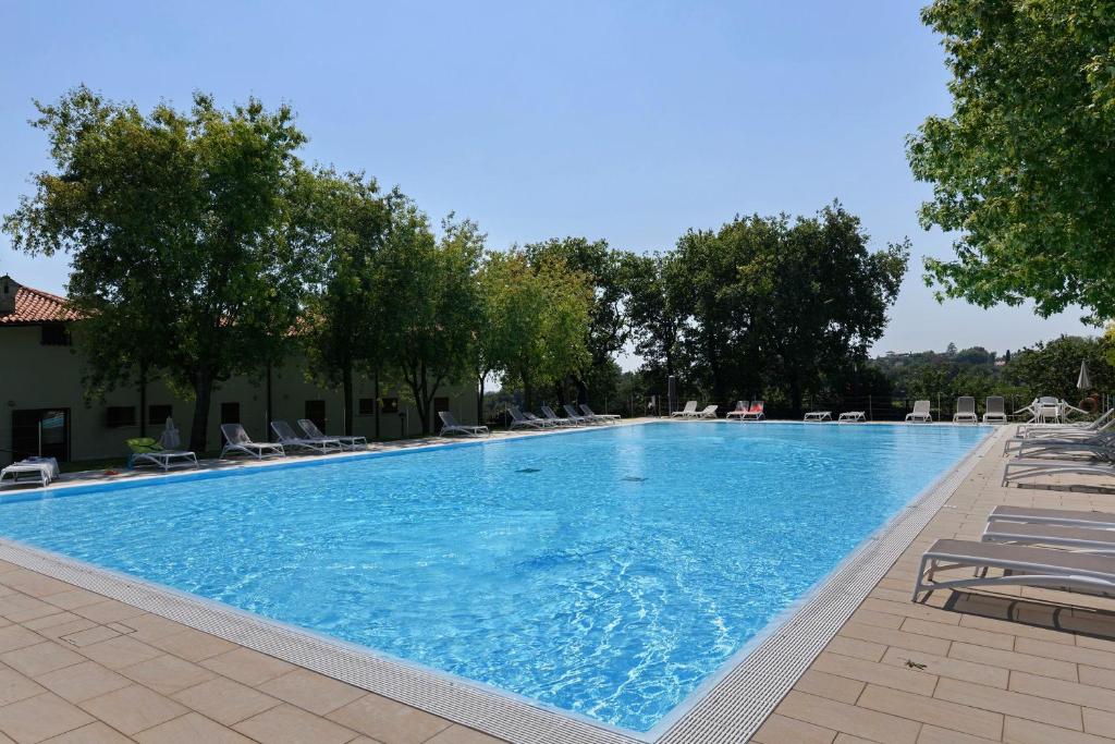a large swimming pool with chairs and trees at Residenza Le Paolette con piscina in Padenghe sul Garda