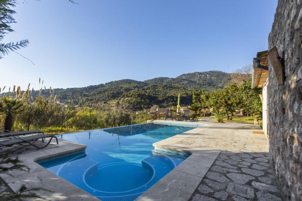 a blue swimming pool with a mountain in the background at Es Tarongers in Sóller