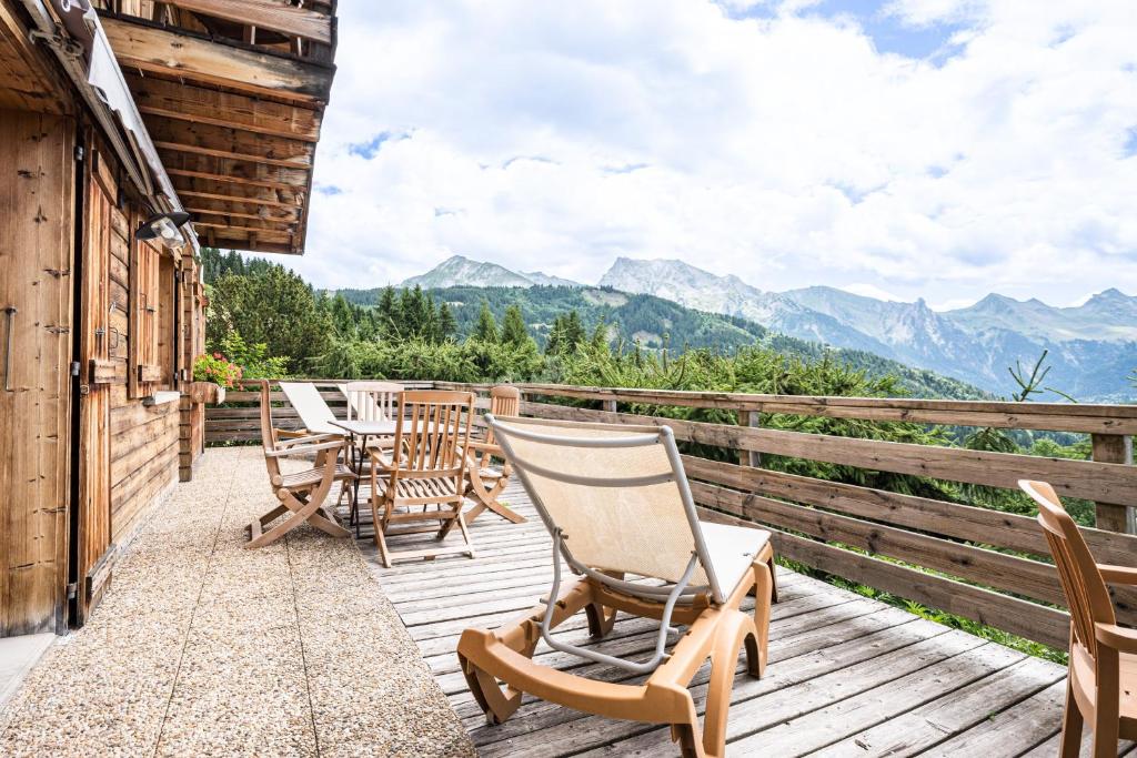 a deck with chairs and tables with mountains in the background at Chalet Farapreu in Manigod