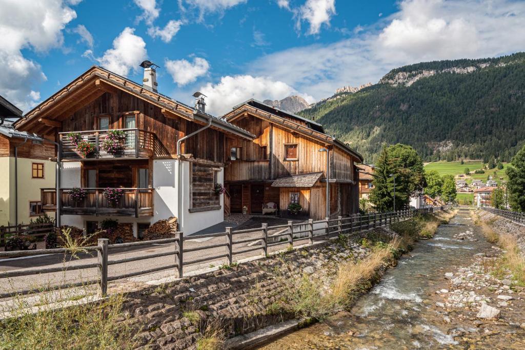 a house in the mountains next to a river at Appartamento Tobià in Pozza di Fassa
