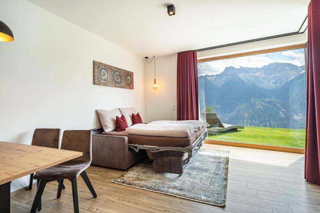 a living room with a couch and a large window at Paflur Lodges Abendrot in Lasa