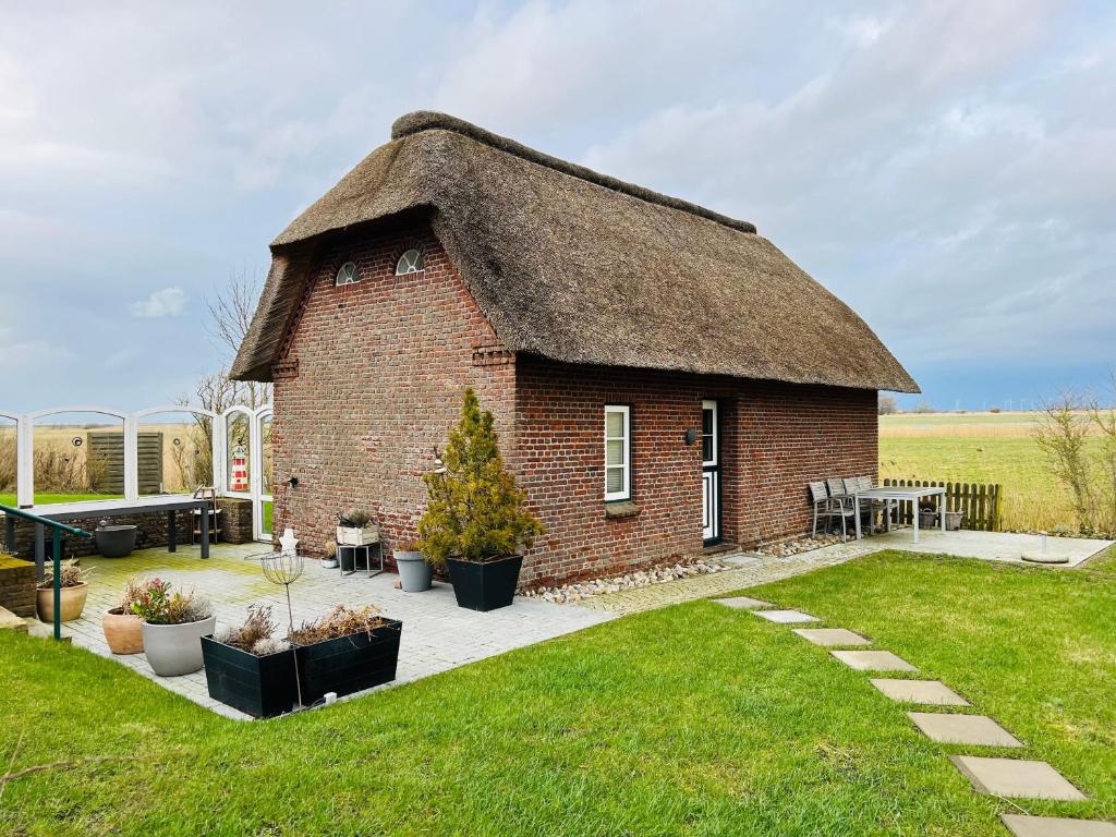 a small brick building with a grass roof at Hyggelig Am Deich - Ockholm in Ockholm