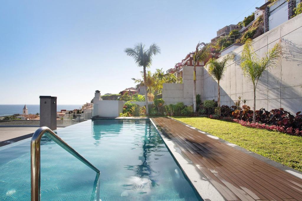 a swimming pool in front of a building with the ocean at Casa Castanheta in Câmara de Lobos