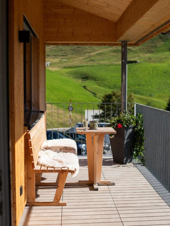 a wooden porch with a bench and a table at Alpenpanorama Konzett Faschina in Fontanella