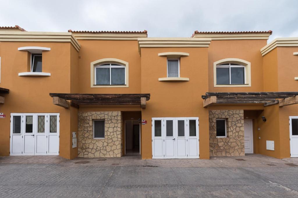 a large orange house with white garage doors at Casa Angel A 3 in Corralejo