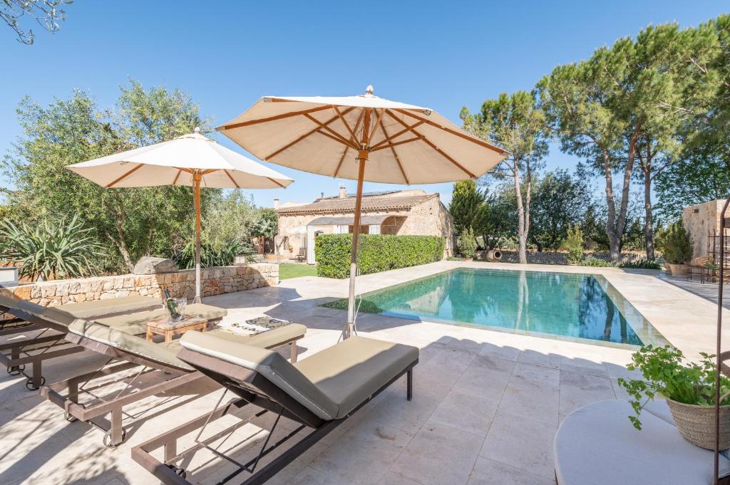 a patio with a table and umbrella and a swimming pool at Es Lledoner 2 in Islas Baleares