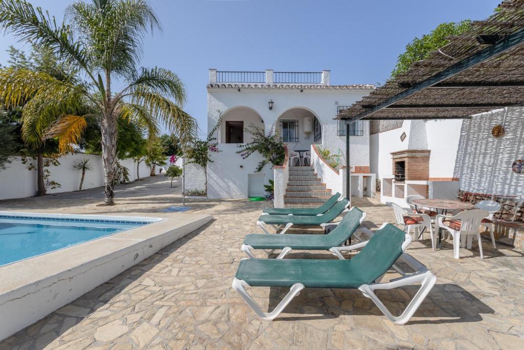 a row of lounge chairs next to a swimming pool at Cortijo Encarni in Frigiliana
