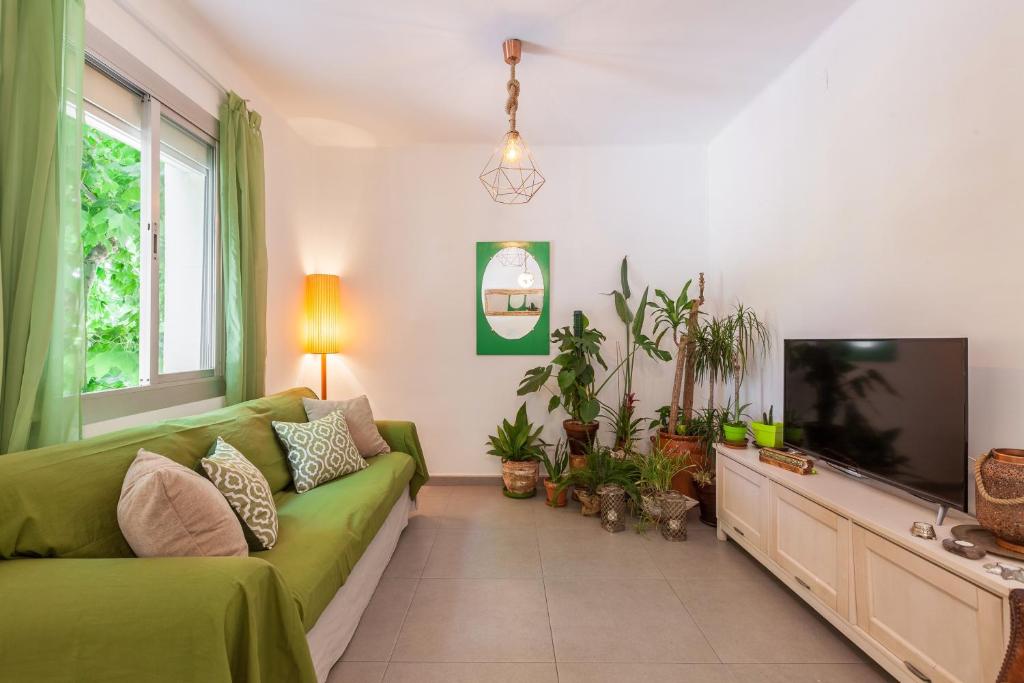 a living room with a green couch and a flat screen tv at Boutique Beach Mataró in Mataró