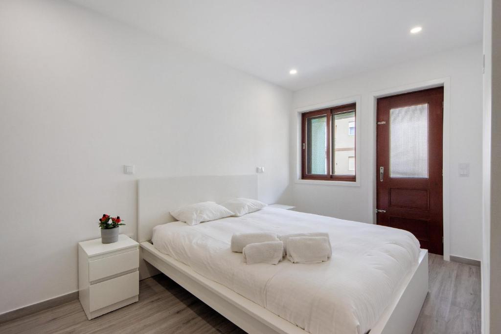 a white bedroom with a large white bed with two pillows at T4 Furadouro with sea view in Ovar