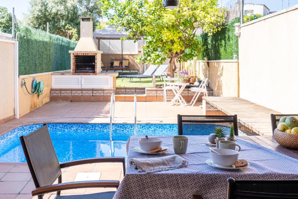 a table with plates of food on it next to a pool at another day in paradise in Calafell