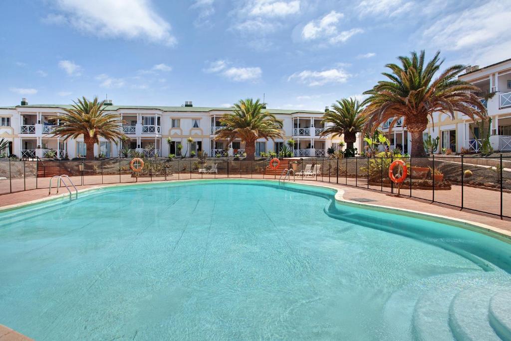 a large swimming pool in front of a hotel at Casa Verdemar in Corralejo