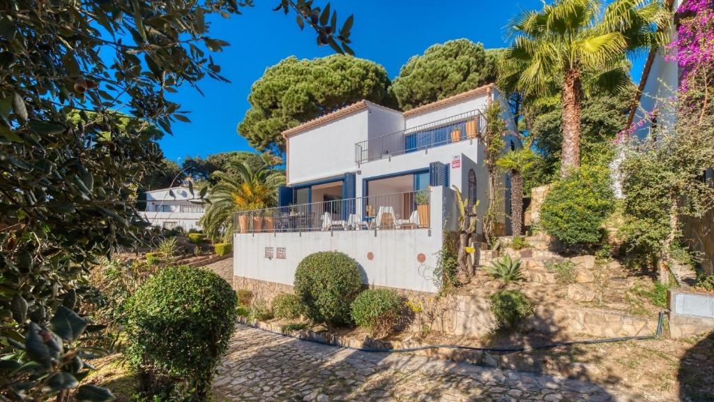 a house on a hill with trees and bushes at Costacabana - Casa Adora in Tossa de Mar