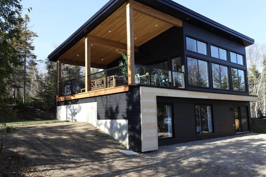 a house with a large deck on the side of it at Chalet Le Select - Private Spa with River View in Les Éboulements
