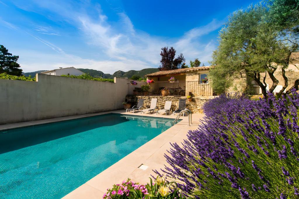 a swimming pool in a yard with purple flowers at Maison L'oustalette De Mau-bé in Maubec