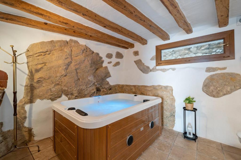 a bathroom with a tub in a stone wall at El racó de les escales in Tivissa