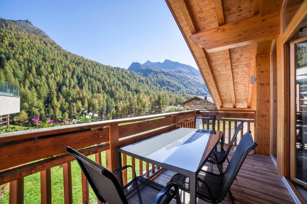 a balcony with a table and chairs and mountains at Ferienwohnung Edelweiss in Pfelders