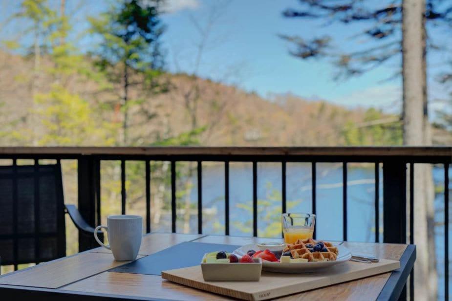 a table with a plate of food and a glass of orange juice at Luft Skift Spa - Waterfront & Private Spa in Lac-aux-Sables