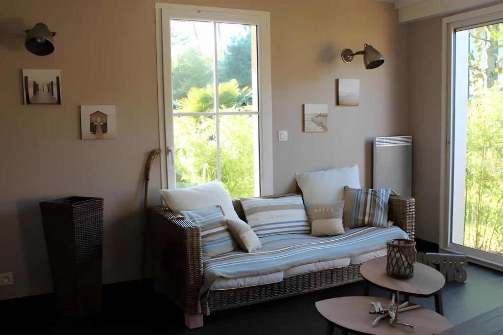 a wicker couch in a room with a window at Maison Ô'5 Avec Terrasse in Lanton