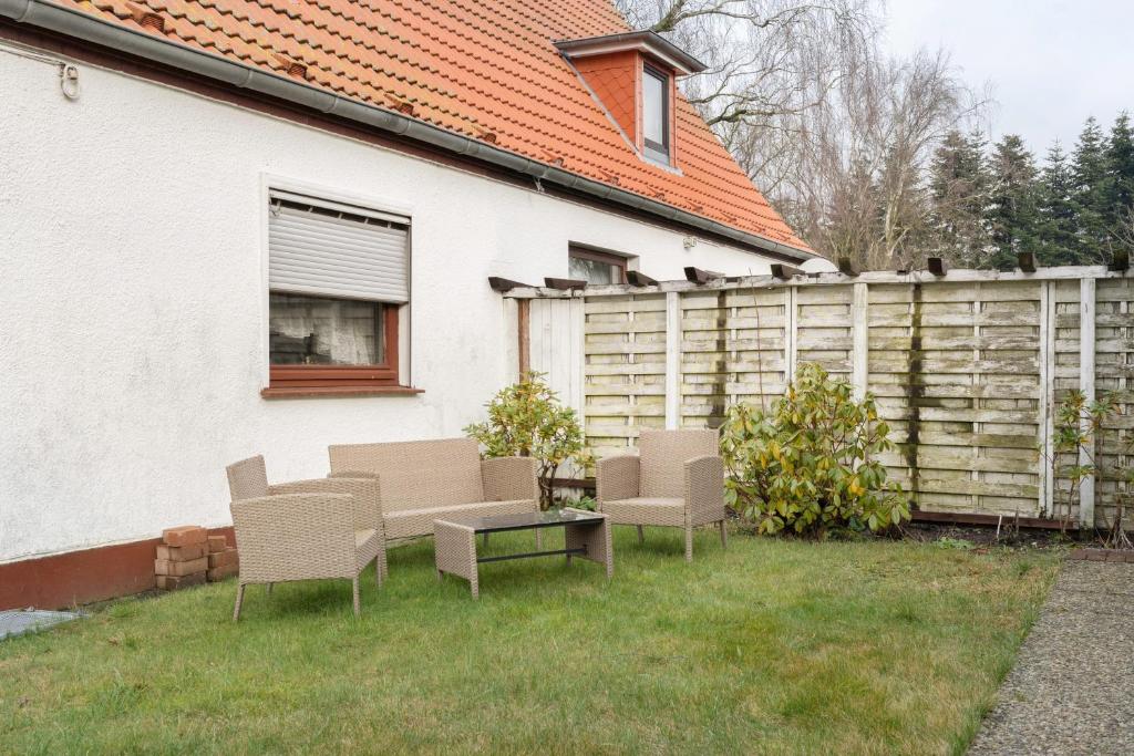 a yard with chairs and a table and a fence at Ferienwohnung Weyres in Fleckeby
