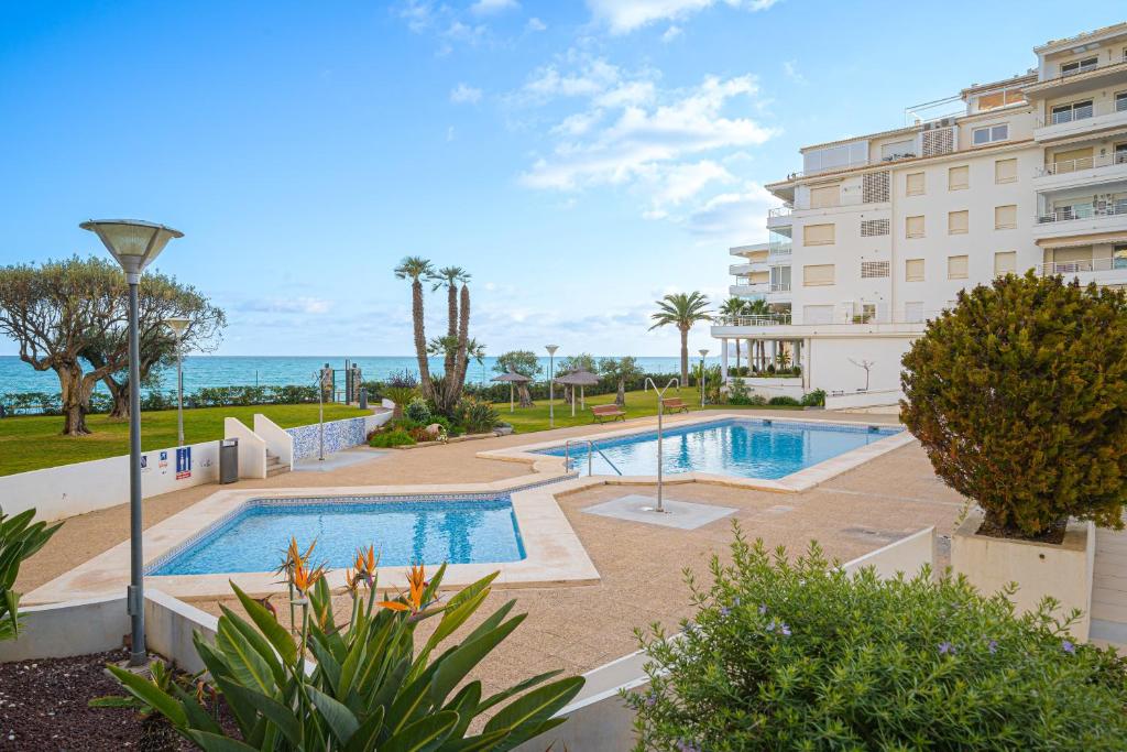 a building with a swimming pool next to the ocean at Costa Bella in Altea