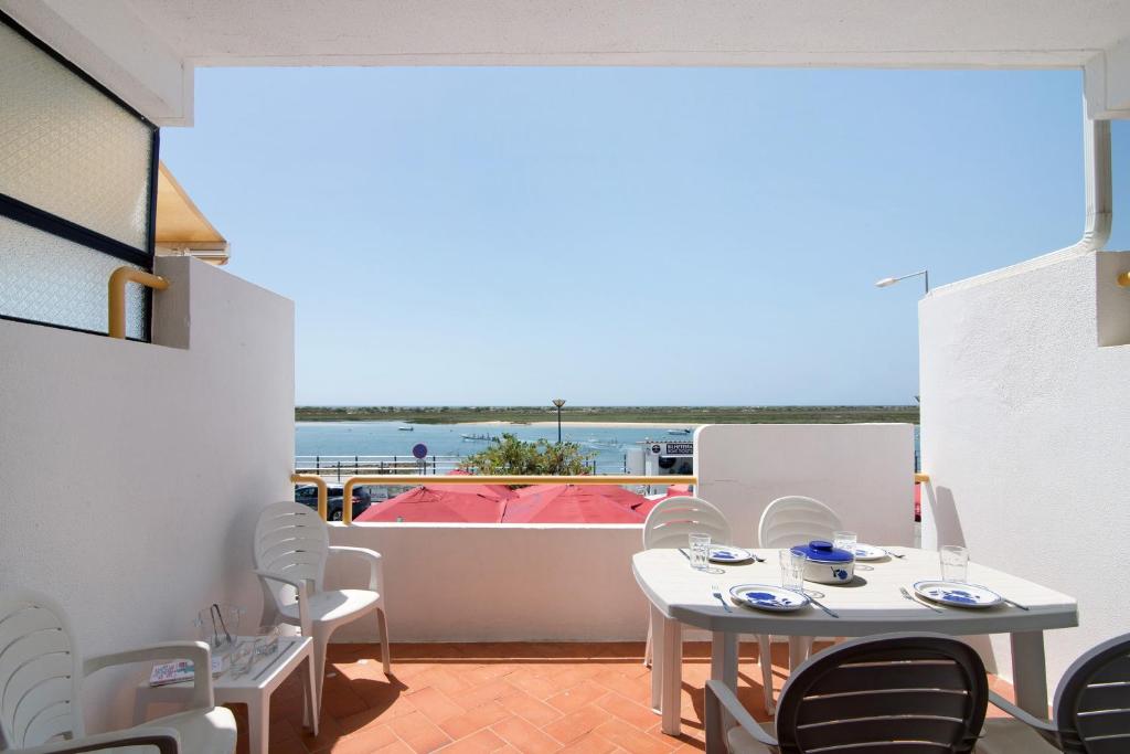 a balcony with tables and chairs and a view of the ocean at Cabanas Mar 94 in Cabanas de Tavira