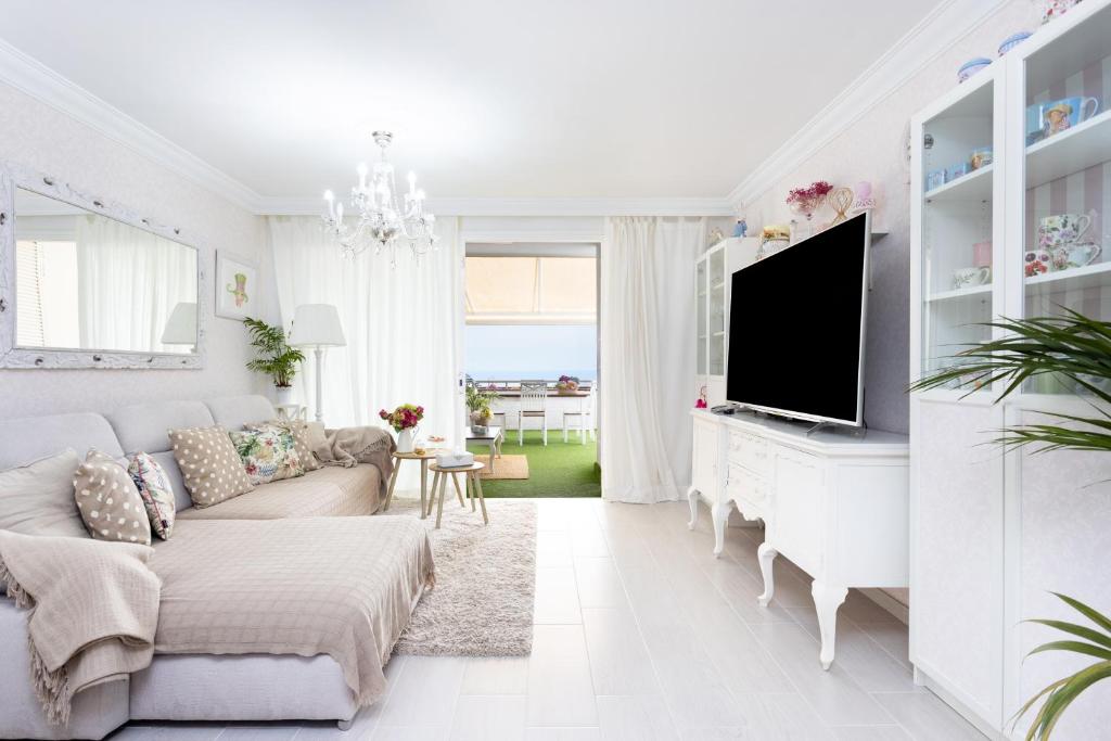 a white living room with a couch and a tv at Sunset Costa Adeje Oceanview in Adeje