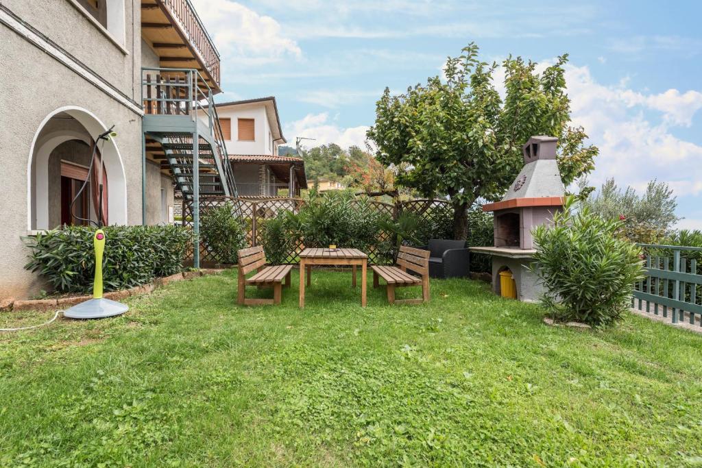 a yard with benches and a table and a grill at App Oleandro Casa Demonti in Tignale