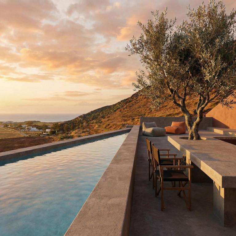 a pool with a table and chairs next to the water at Anzo Villas in Oia