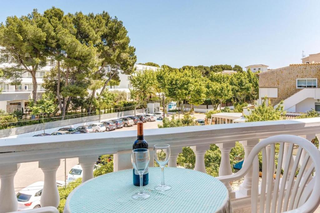 a bottle of wine and two glasses on a table on a balcony at Apartamento La Cabanya 3a in Canyamel