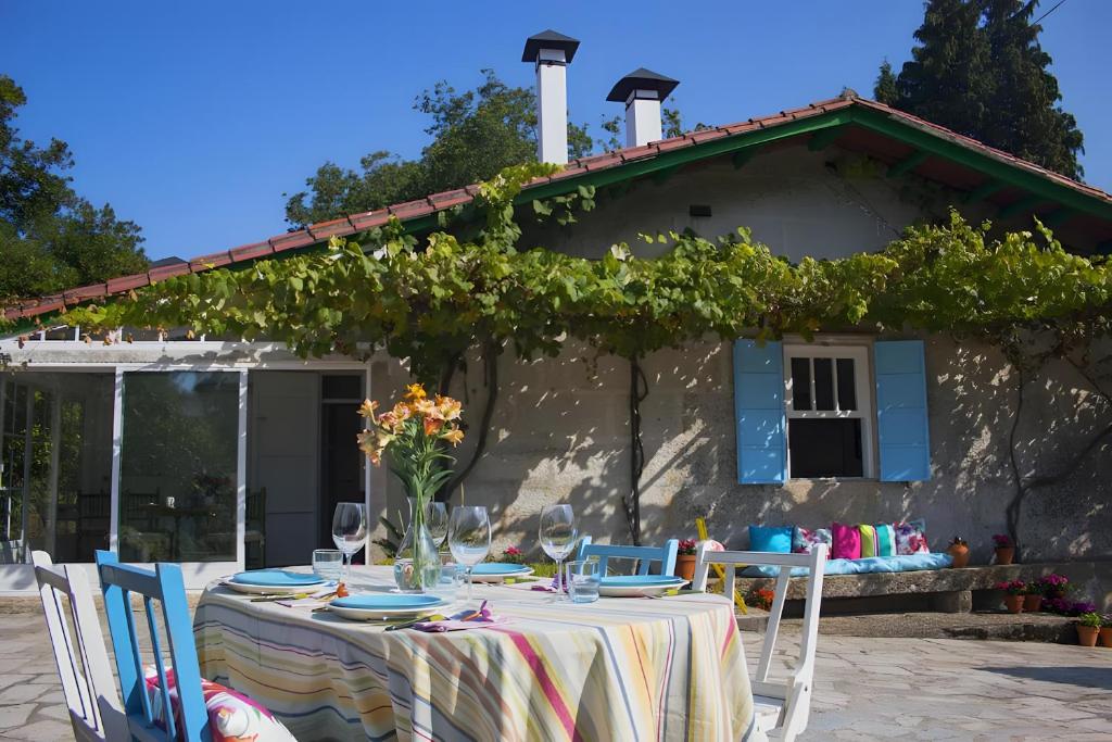 a table with chairs and wine glasses in front of a house at Casa Con Encanto in Bueu