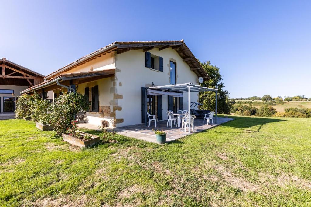 a farmhouse with a table and chairs in a yard at Le Basque - Bazas in Bazas