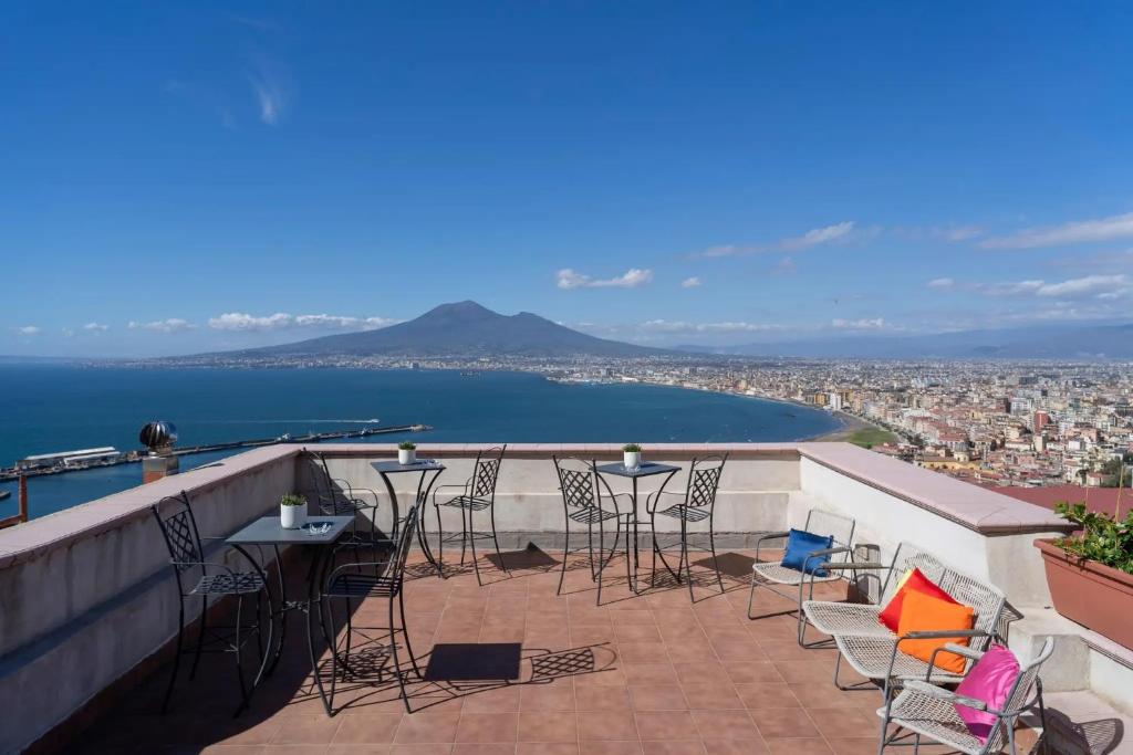a balcony with chairs and tables and a view of the water at Le Suite del Castello in Castellammare di Stabia