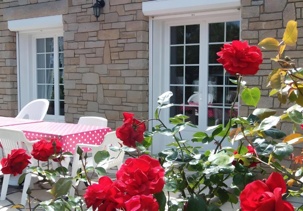 a table and chairs on a patio with red roses at Maison d'Hôtes - La Marée Hôtes in Piriac-sur-Mer