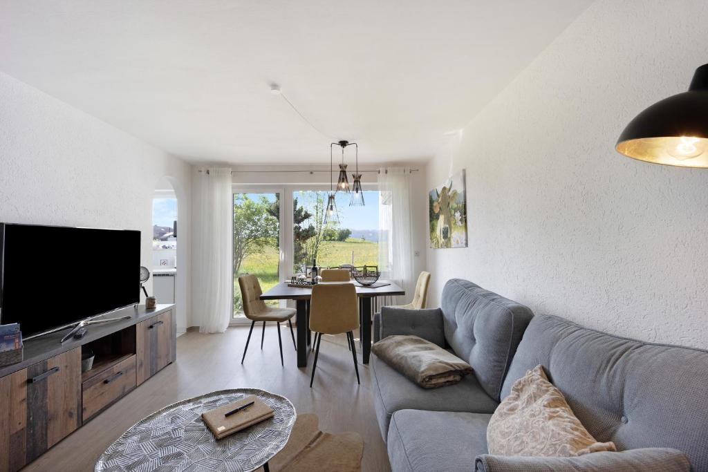 a living room with a couch and a tv and a table at Landliebe – Seenähe & Grüntenblick in Petersthal