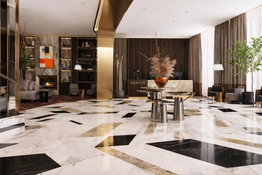 a lobby with a table and chairs and a fireplace at Three Corners Hotel in Skopje
