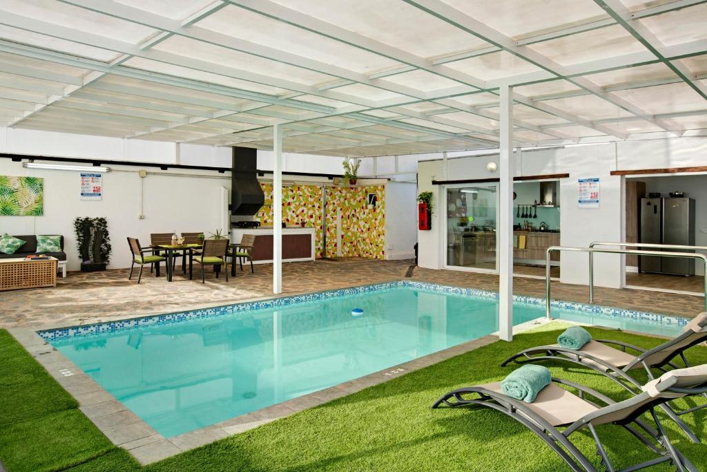 a pool with two chairs and a table and a house at Los Cipreses in Ingenio