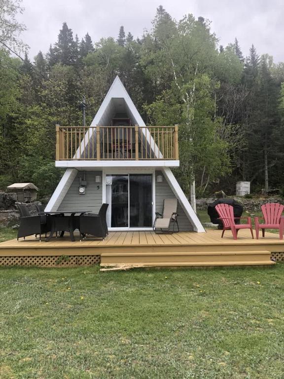 a house with a deck with chairs on it at Chalet Le Pointu - St-Lawrence River View in Rivière-du-Loup