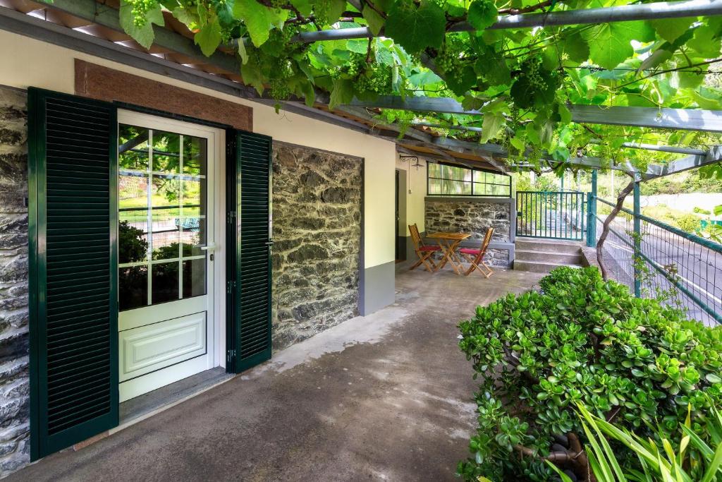 an outdoor patio with a door and some plants at Villa Rústica - Casa da Lurdes in Ribeira Brava