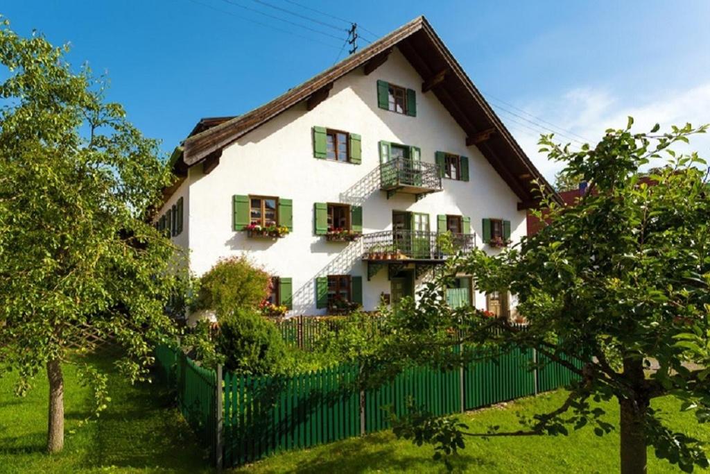 a white house with green shutters and a fence at Ferienwohnung Filser in Unterammergau