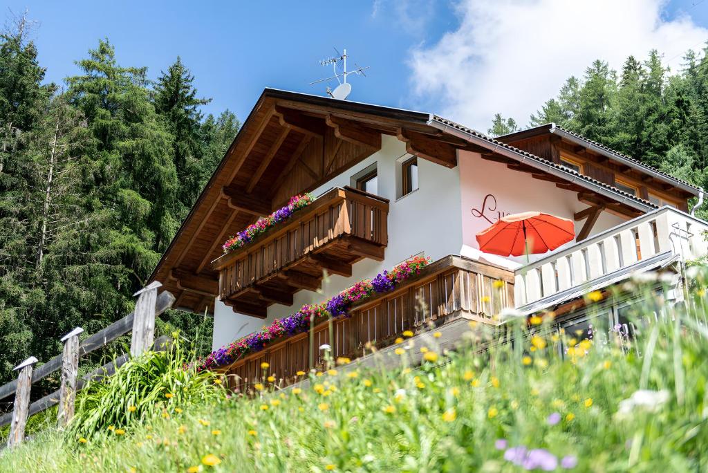a house with a balcony with a red umbrella at Mair am Tinkhof in Selva dei Molini