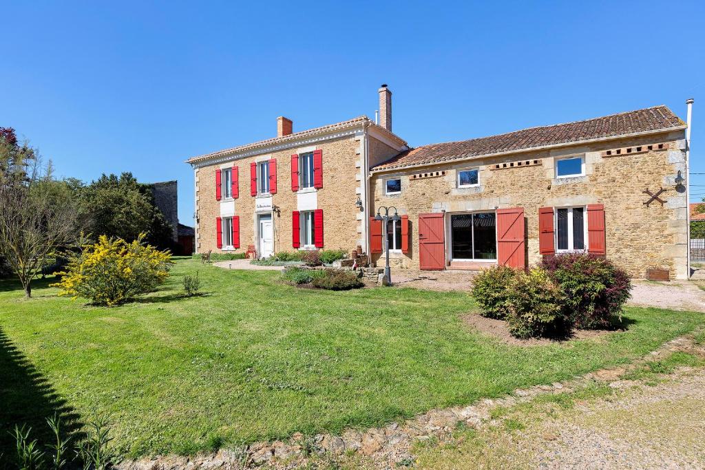 an old brick house with red doors and a yard at Chambres D'hôtes La Baritaudière in La Réorthe