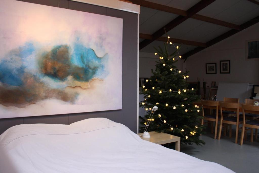 ein Schlafzimmer mit einem Weihnachtsbaum und einem weißen Bett in der Unterkunft Atelier La Luna in Berkenwoude