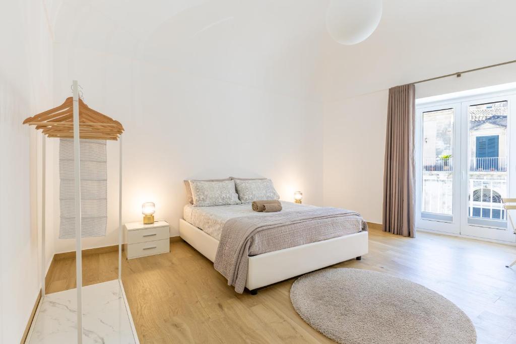 a white bedroom with a bed and a large window at Vico21 nel centro di Modica in Modica