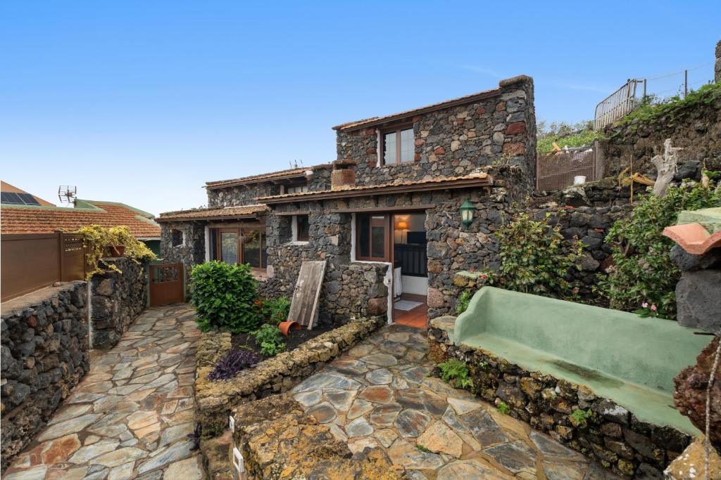 a stone house with a green couch in the yard at Tesbabo Rural - Camelia in Mocanal