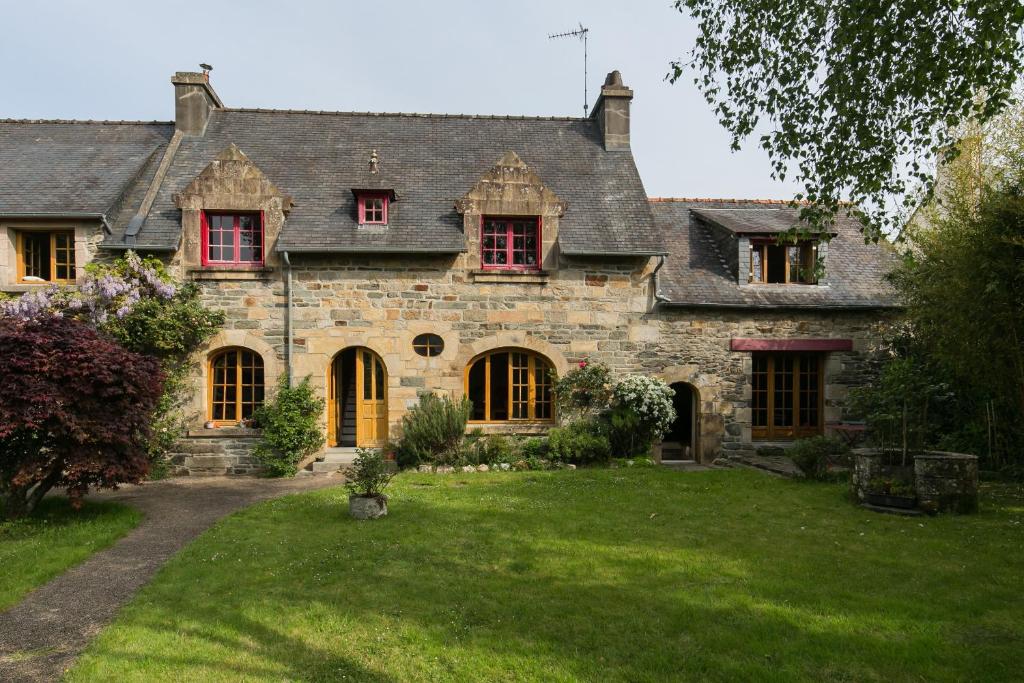 an old stone house with red windows and a yard at Moulin du Tourous - Chambre 1 in Plouédern