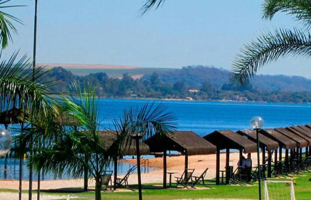 ein Strand mit vielen Sonnenschirmen und einem Gewässer in der Unterkunft Casa na Represa do Broa - Condomínio Vila Pinhal in Itirapina