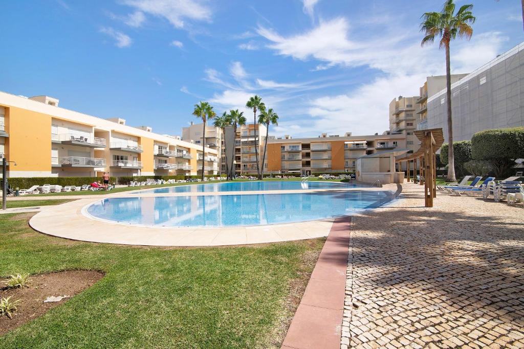 a swimming pool in a resort with palm trees and buildings at Vilamoura Marina in Vilamoura